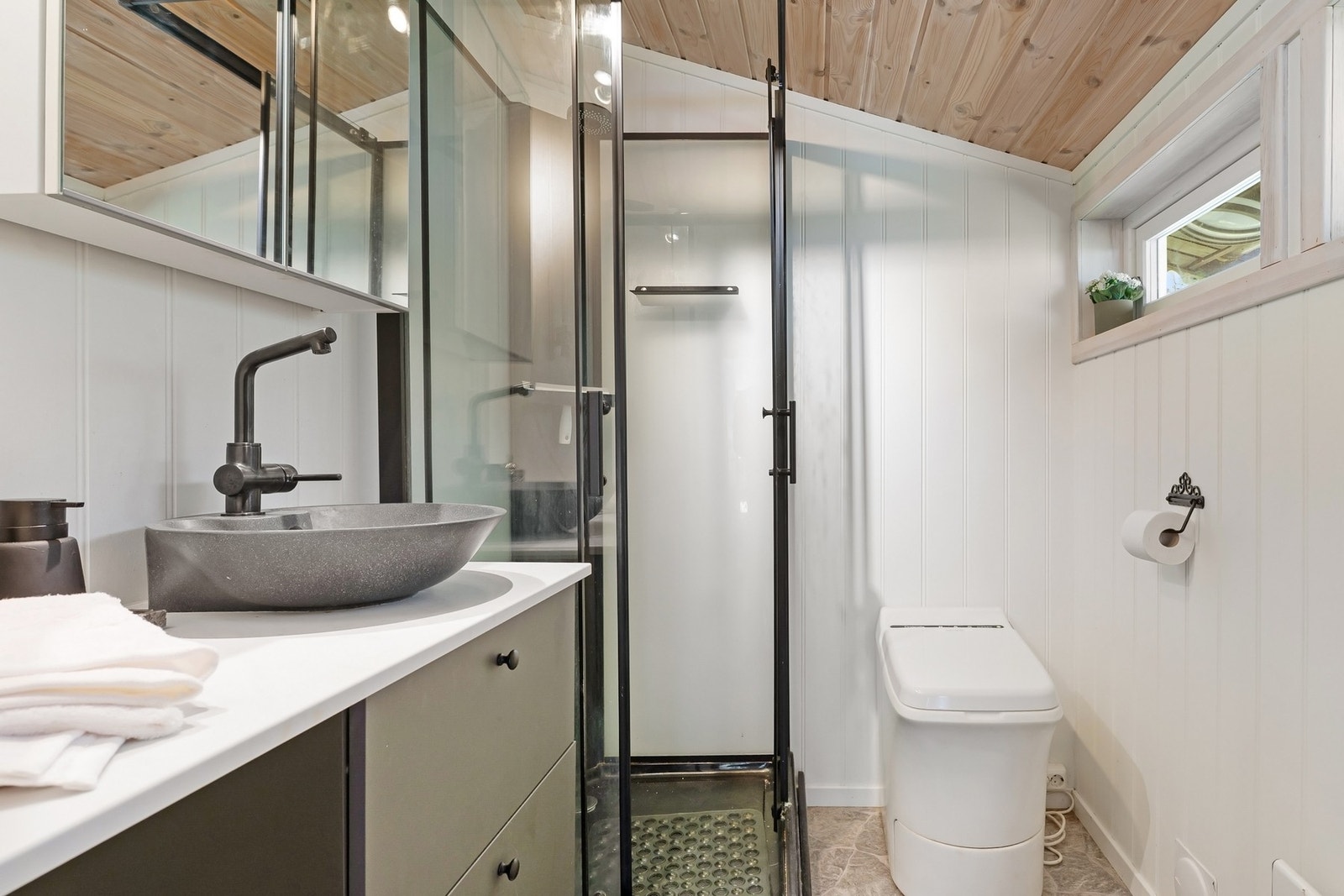 Badet er innredet med dusj, servant og forbrenningstoalett. Galleribilde