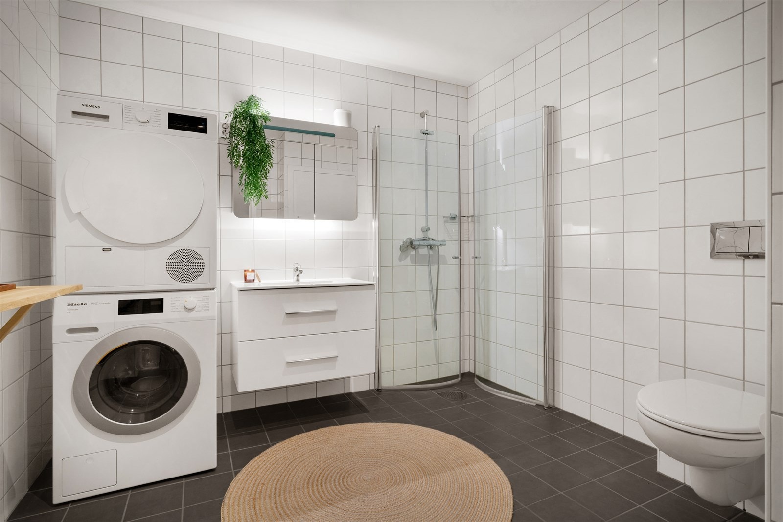 - Badet inneholder benkeskap med servant, dusjdører, vegghengt toalett og opplegg for vaskemaskin - Galleribilde