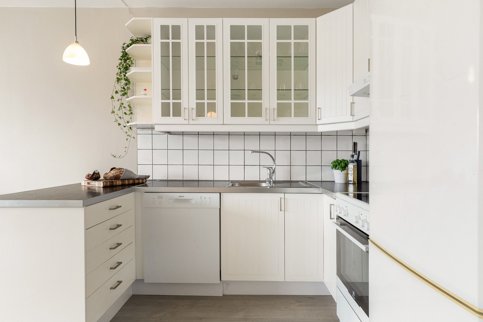 Innredningen har naturlig plass til frittstående hvitevarer som stekeovn, oppvaskmaskin og kjøle-fryseskap. Videre har innredningen laminat benkeplate med nedfelt vask og montert downlights under overskap. Galleribilde