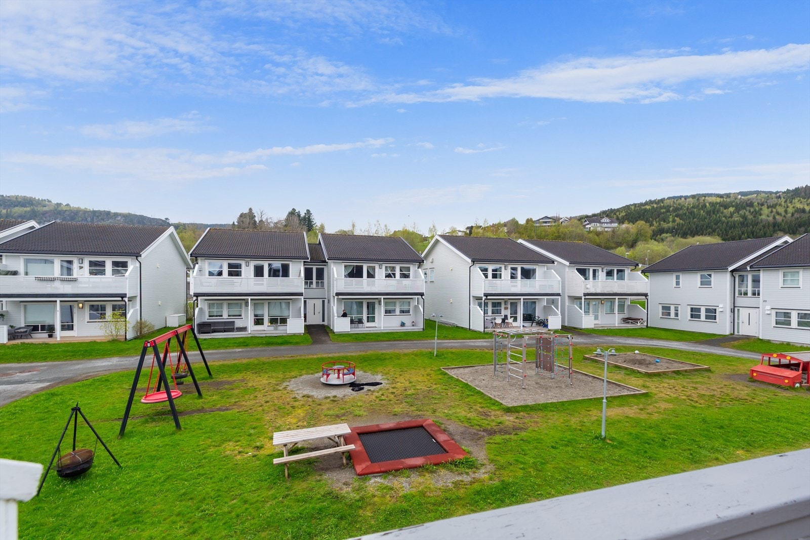 Fra balkongen har du utsyn mot den hyggelige felles lekeplassen, som gir både liv og et åpent, trivelig nabolagsmiljø. Galleribilde