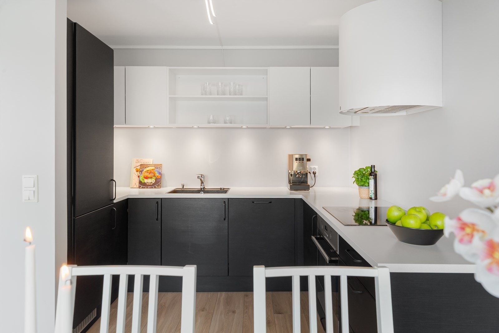 Kjøkkenet har integrerte hvitevarer, stilfull komfyrhette og rikelig med benke- og skapplass. Spotter under overskap gir godt og funksjonelt arbeidslys på kjøkkenbenken Galleribilde