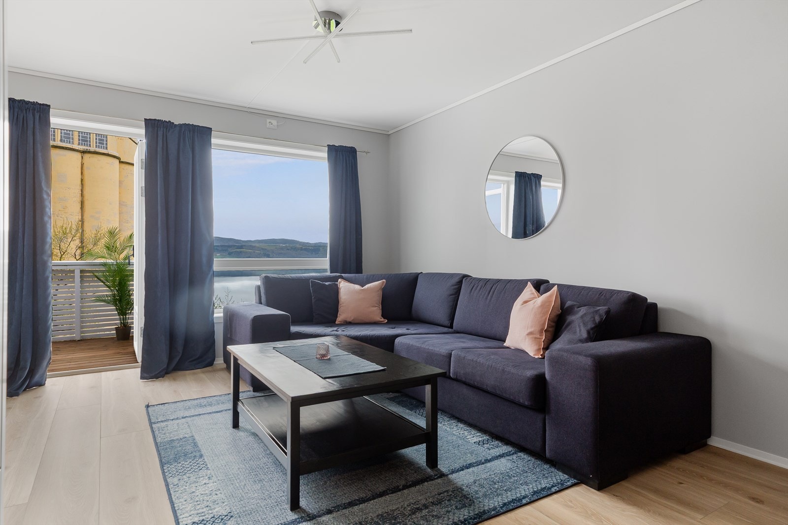 Lys og romslig stue med åpen løsning mot kjøkkenet, enstavs gulv og lyse veggflater. Galleribilde