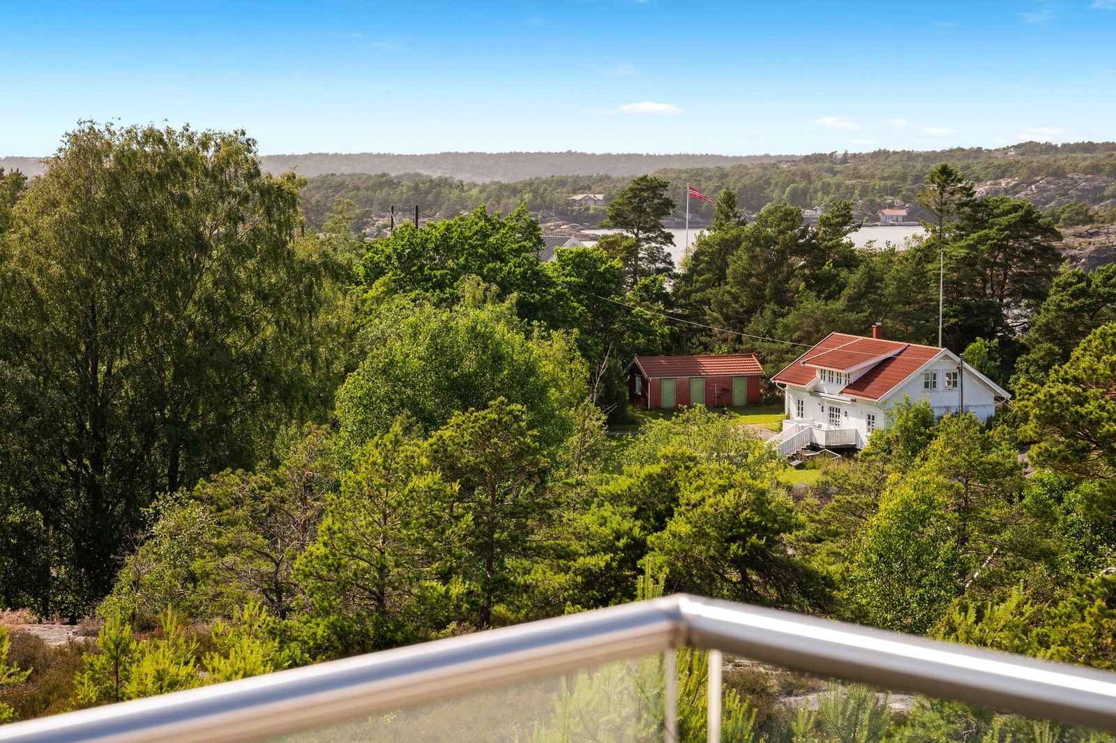 Det er glassrekkverk montert rundt verandaen og litt utsikt mot sjøen Galleribilde
