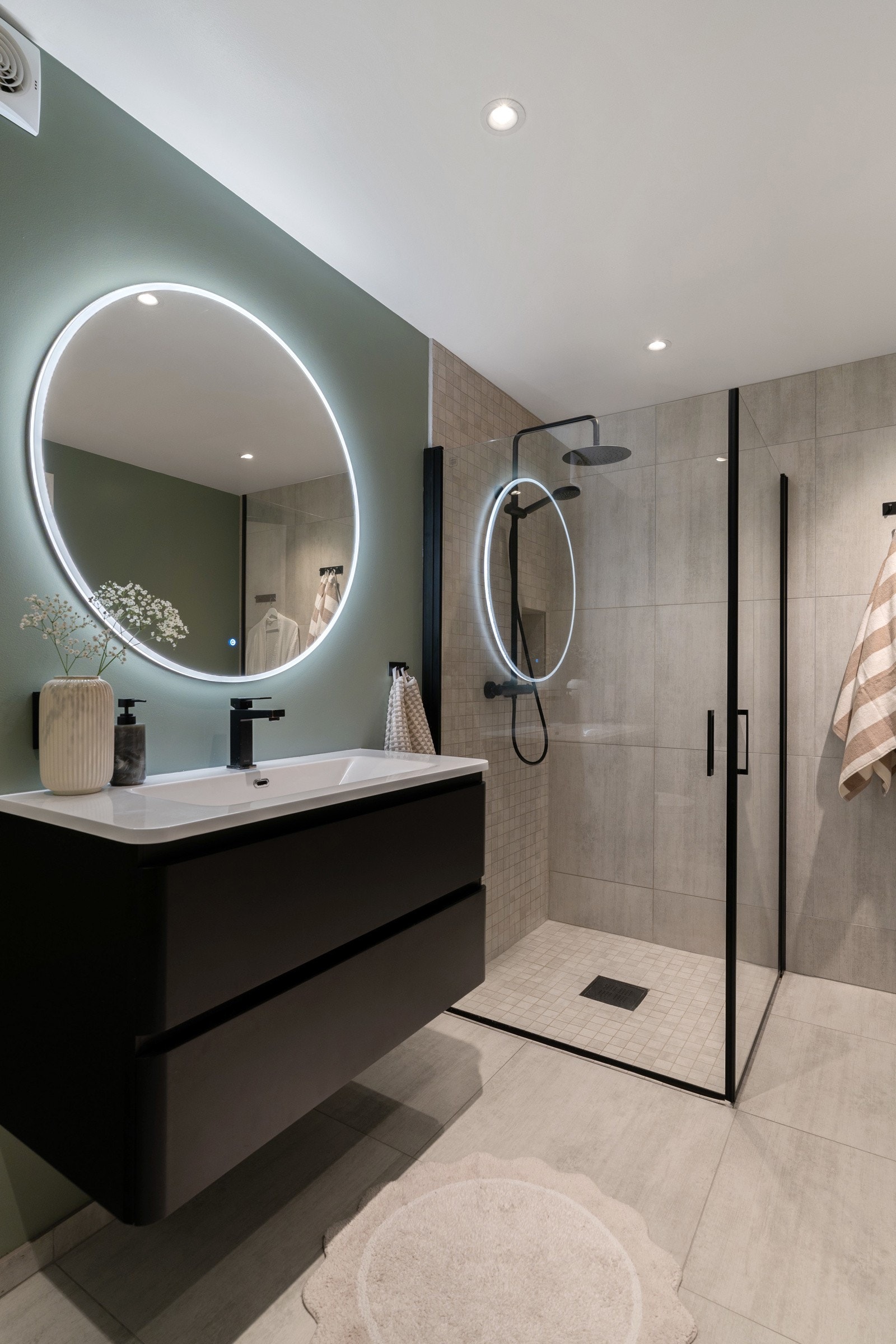 Badet er utstyrt med servant i en pen innredning, speil med ledlys, praktiske dusjvegger, regndusj, vegghengt wc og downlights. Galleribilde