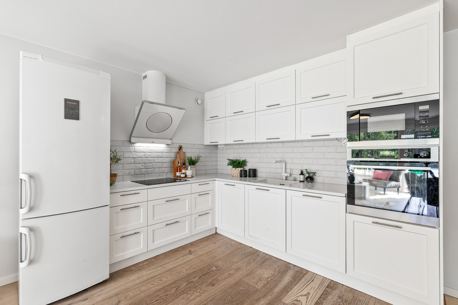 Kjøkkenet har en stilren innredning med fabrikkmalte, profilerte fronter som gir et klassisk og tidløst uttrykk. Benkeplaten i slitesterk kompositt gir både funksjonalitet og et elegant preg. Galleribilde