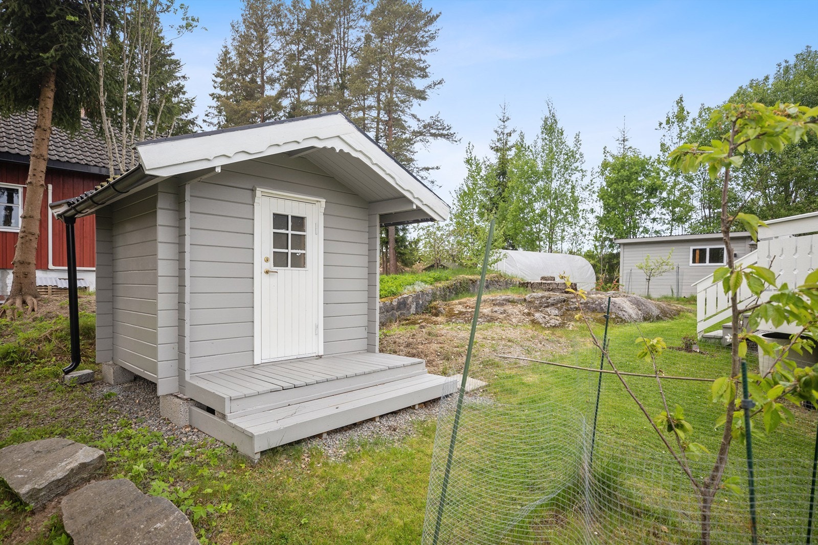 Fra terrassen er det adkomst til en pent opparbeidet hage med gressplen og et sjarmerende dukkehus - et perfekt sted for de små å leke og kose seg. Galleribilde