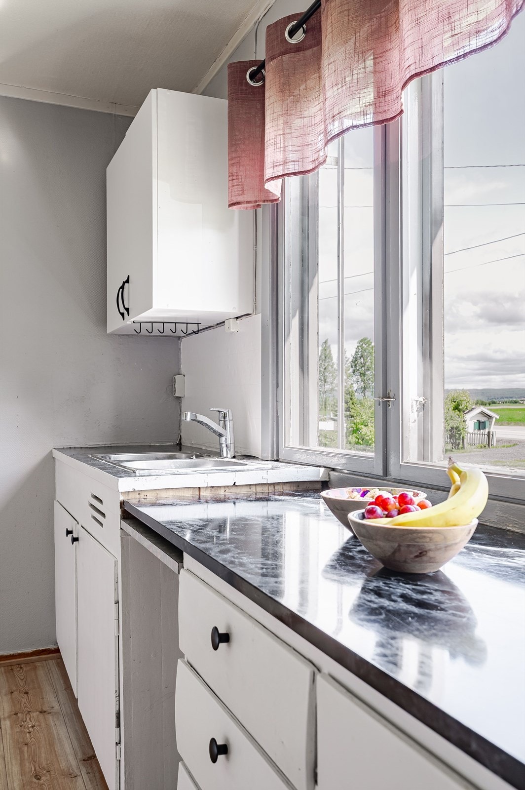 Kjøkkeninnredning med lyse glatte fronter, laminerte og folierte benkeplater med nedfelt vask i rustfritt stål. Galleribilde