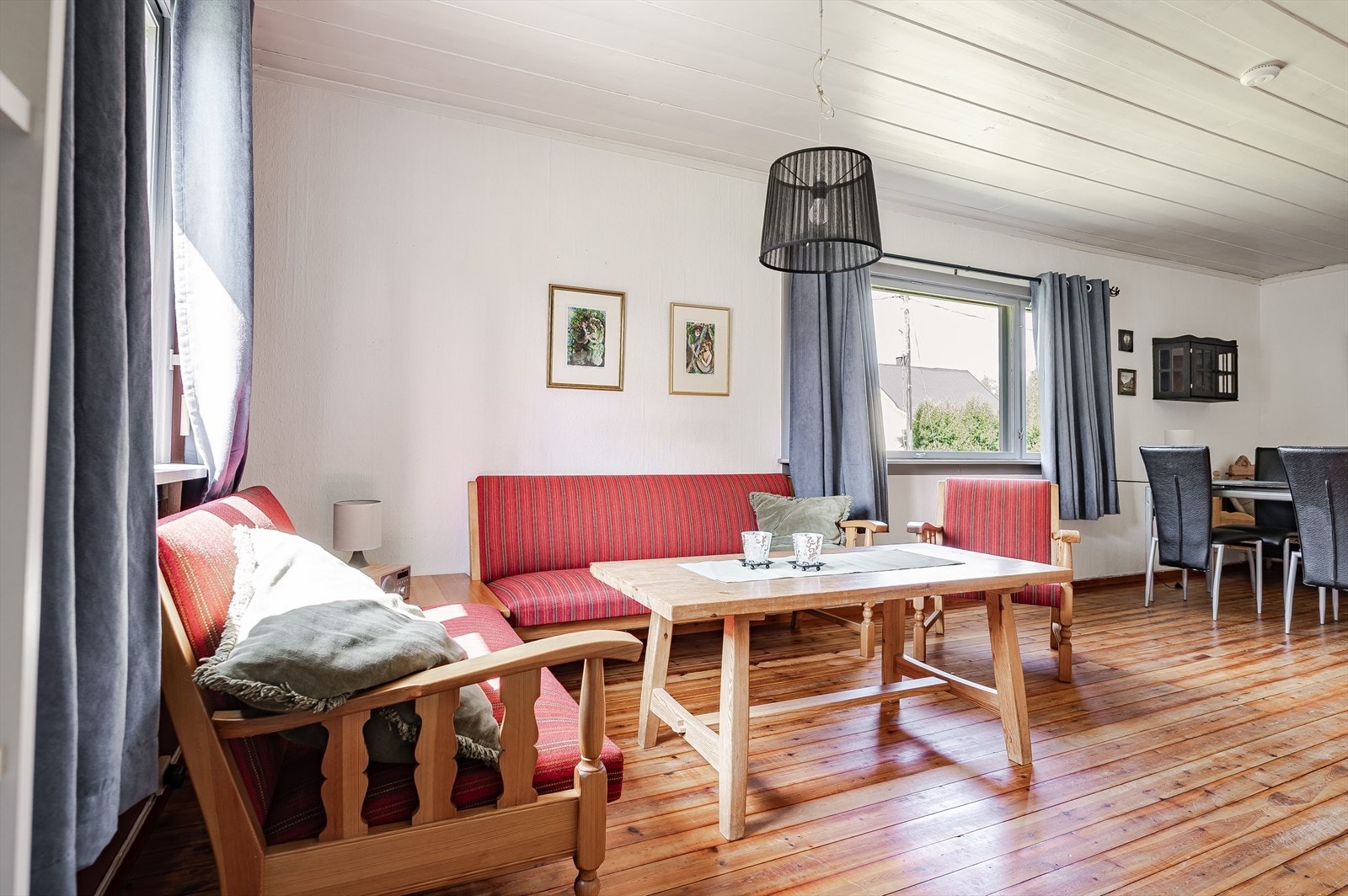 Stuen har lakkerte tregulv og lysmalte overflater med en kontrastvegg i en varm farge. Galleribilde