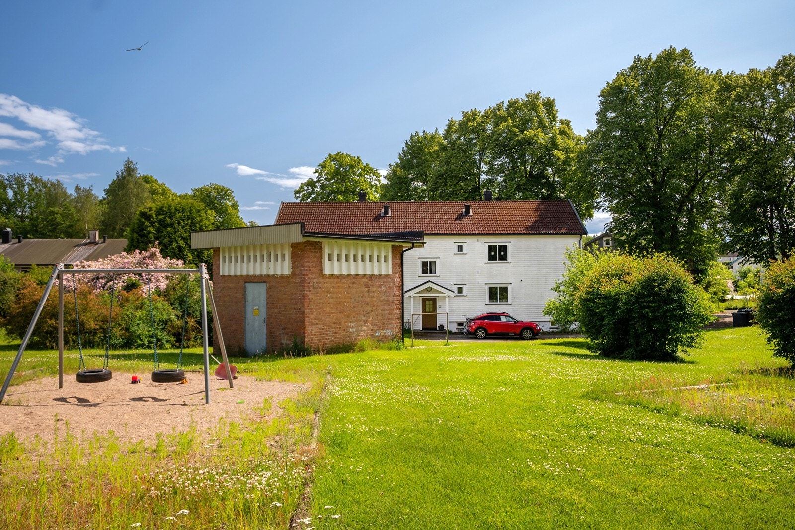 Borettslagets tomt er opparbeidet med gruslagt gårdsplass og hagearealer med plen, busker og hekk, samt gjerde mot veien. Galleribilde