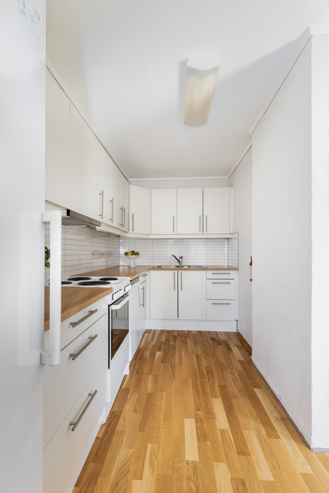Det er montert kjøkkenplater på vegg mellom over og underskap. Laminert benkeplate med gode arbeidsflater med nedfelt oppvaskkum av stål. Galleribilde