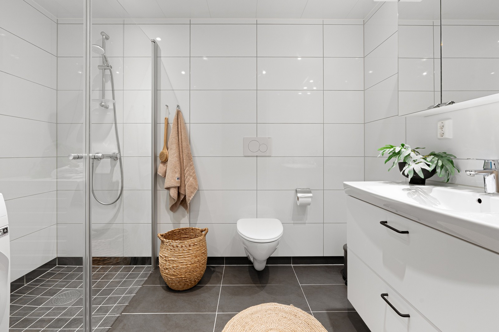 Badet har vegghengt wc, dusjhjørne med regndusj, hånddusj og innfellbare glassdører. Forbruk av varmtvann er inkl.