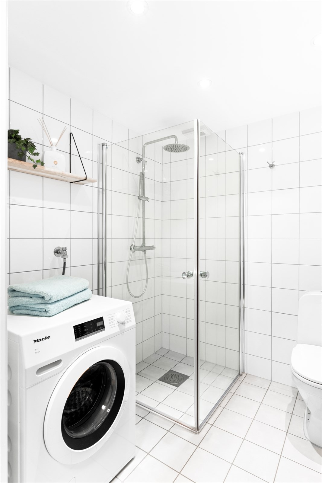 Badet har flislagte vegger og en malt, slett himling med innfelte downlights som gir godt og behagelig lys. Galleribilde