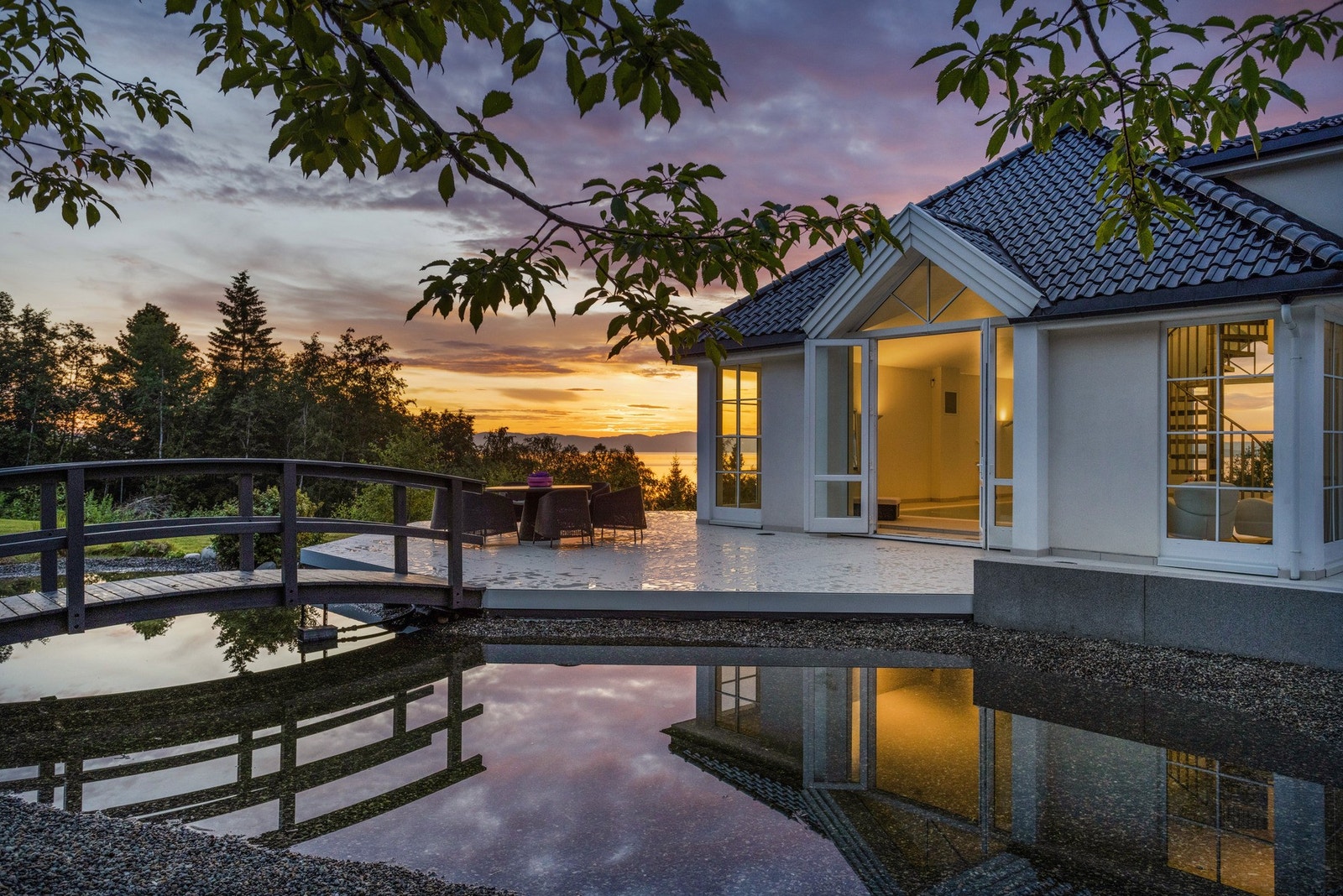 Kveldslyset skaper en magisk ramme rundt uteområdet - med varm glød over fjorden og refleksjoner i vannspeilet. Galleribilde
