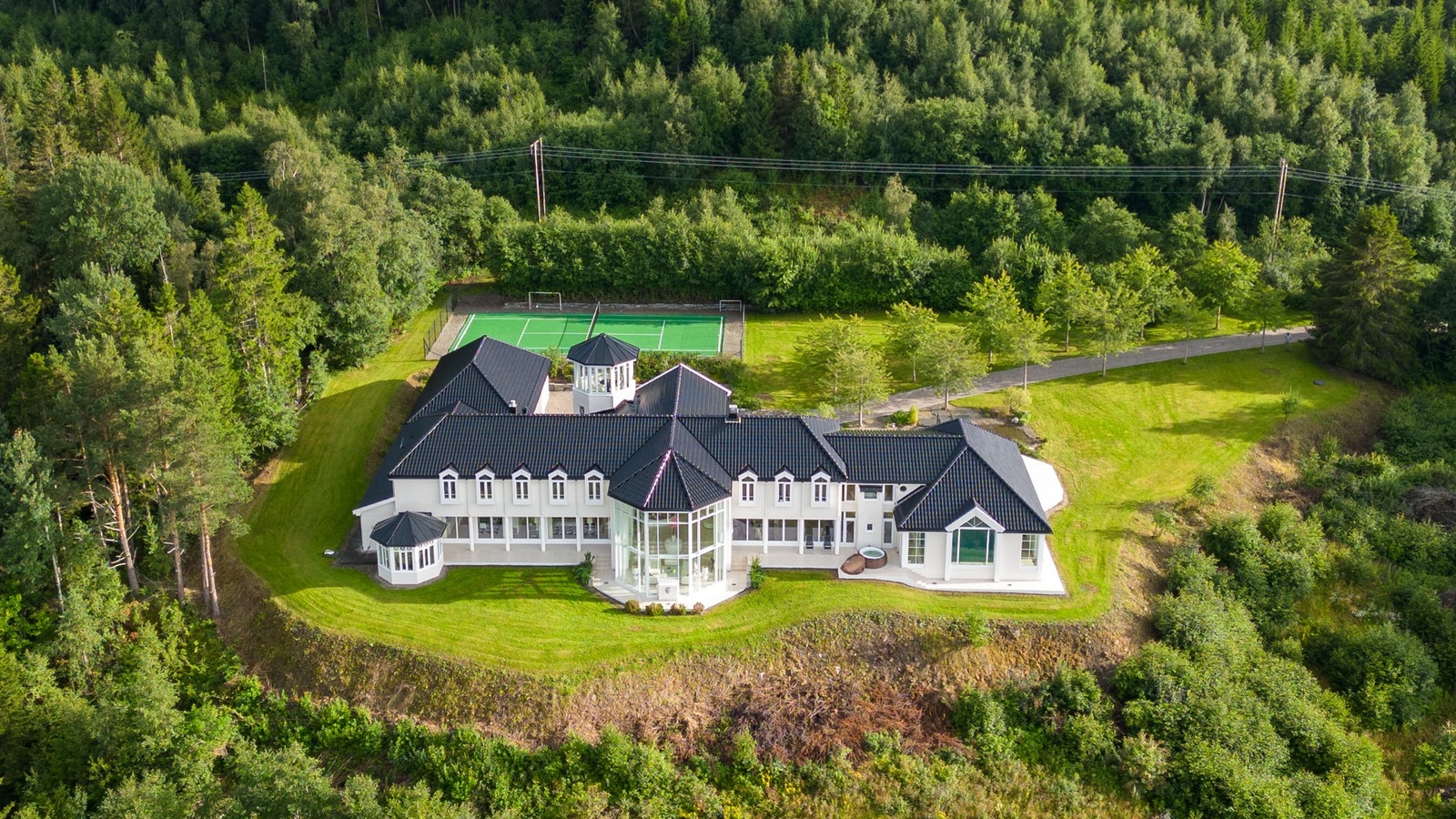 Praktvillaen fra 2010 troner majestetisk på tomten, høyt over fjorden og det frodige nærområdet. Galleribilde