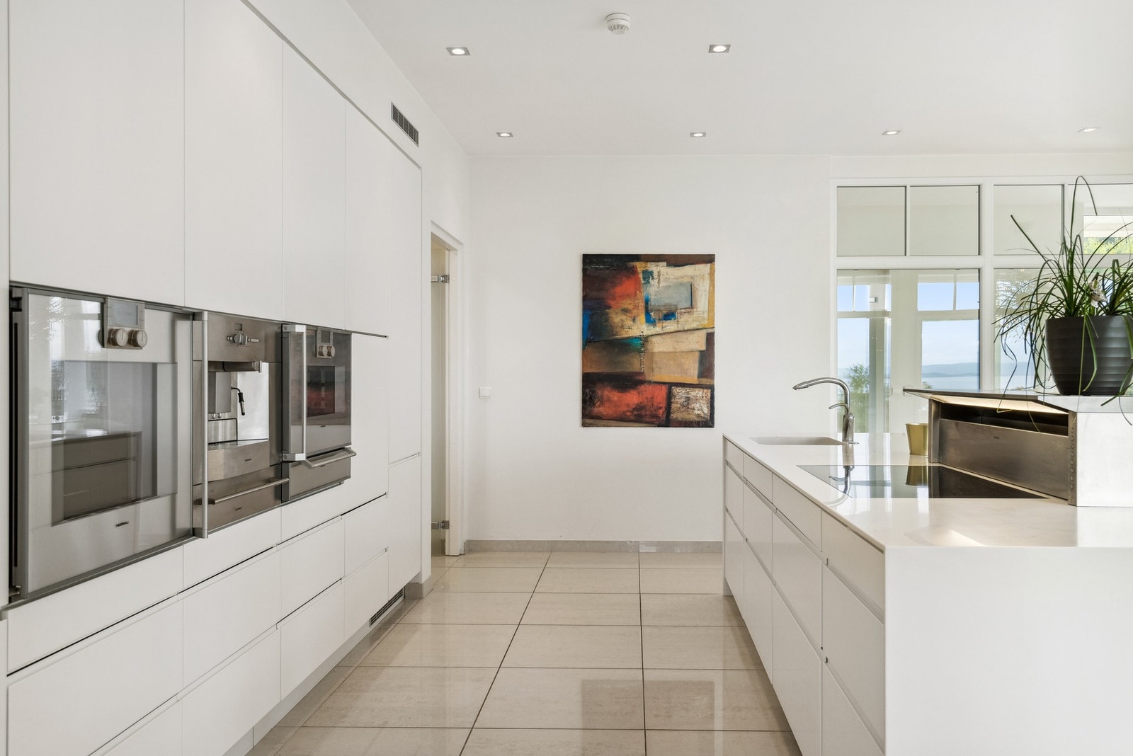 Kjøkkenet gir et eksklusivt og sømløst inntrykk, med integrerte løsninger og en harmonisk palett som fremhever det naturlige lyset. Galleribilde