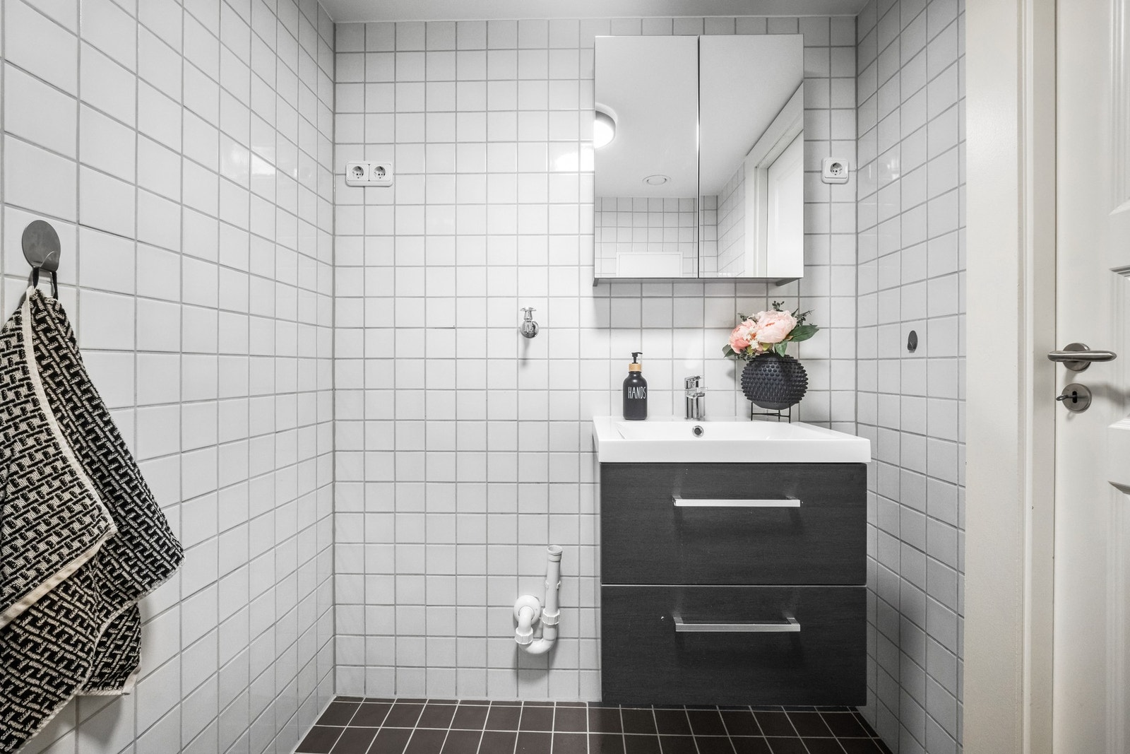 Sort servantinnredning med speilskap på vegg. Det er også plass til tørketrommel Galleribilde