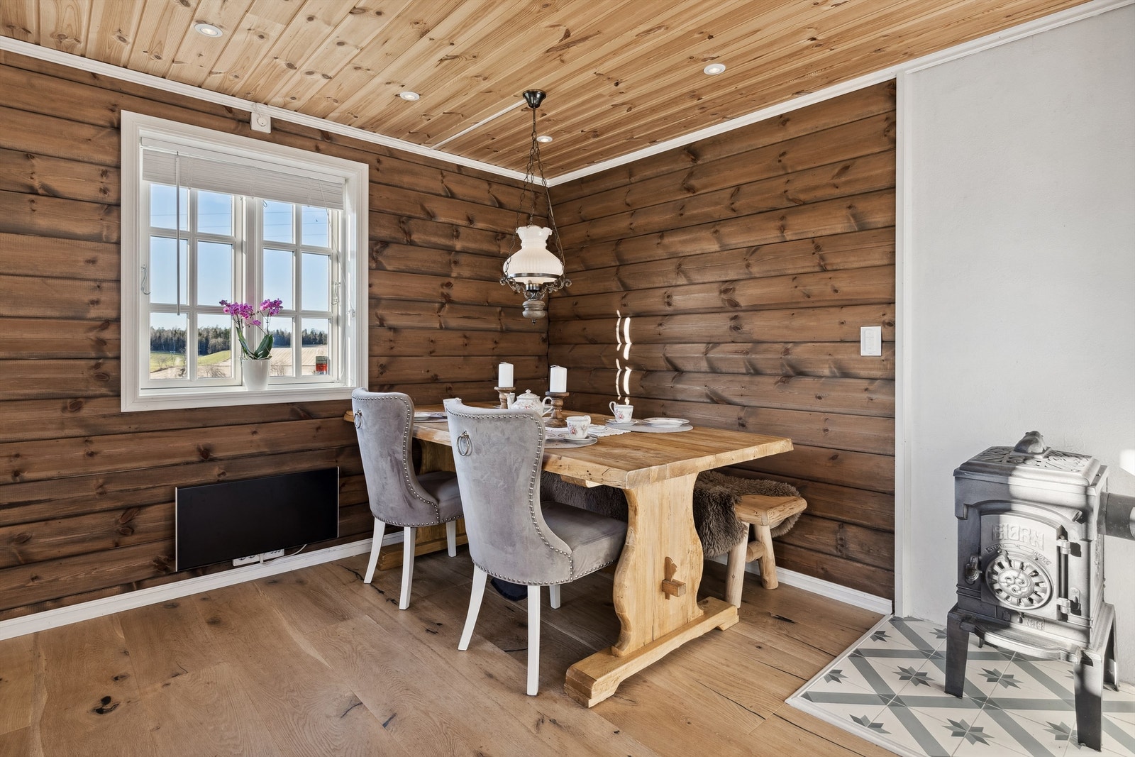 Ved siden av vedovnen på kjøkkenet er det plass til spisebord og stoler Galleribilde