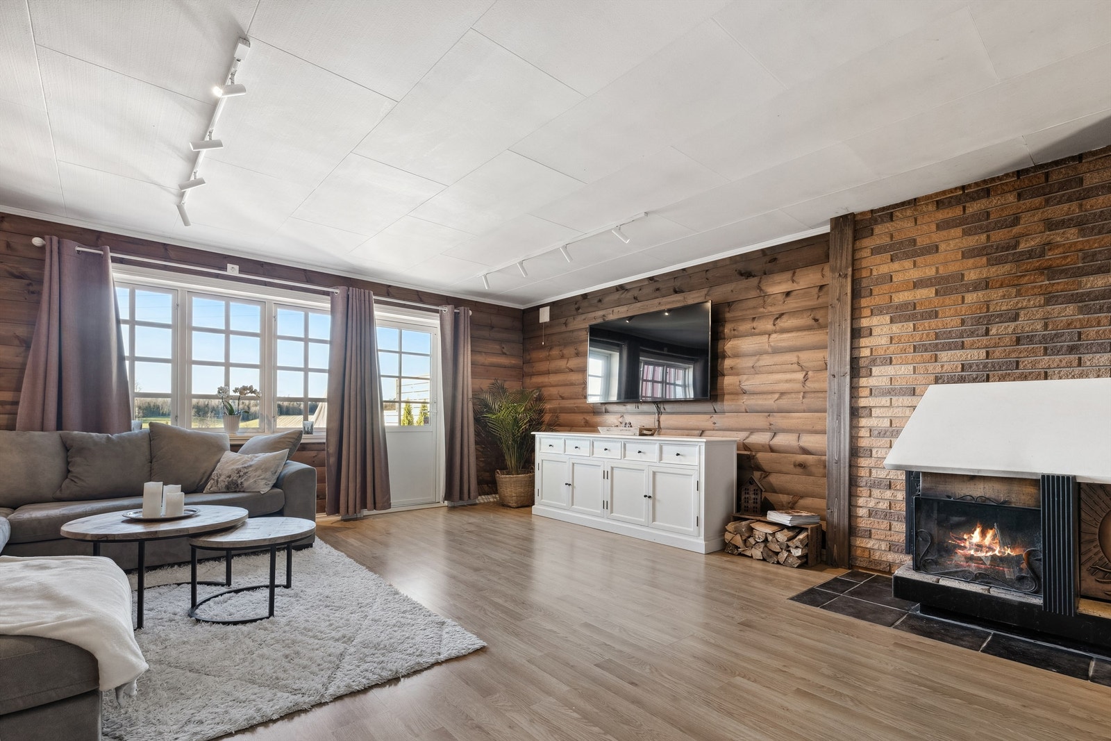 Rommet har åpen peis og store vinduer som slipper inn naturlig lys Galleribilde