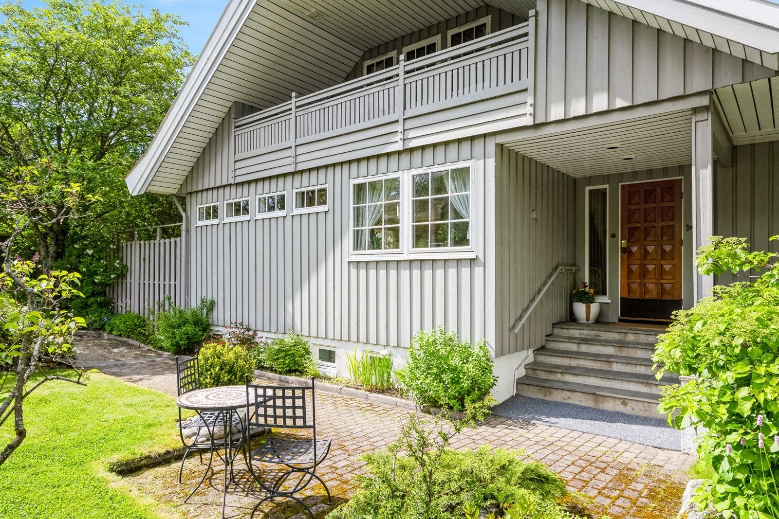 Brosteinsbelagt inngangsparti og beplantet med vakre busker og stauder. Galleribilde