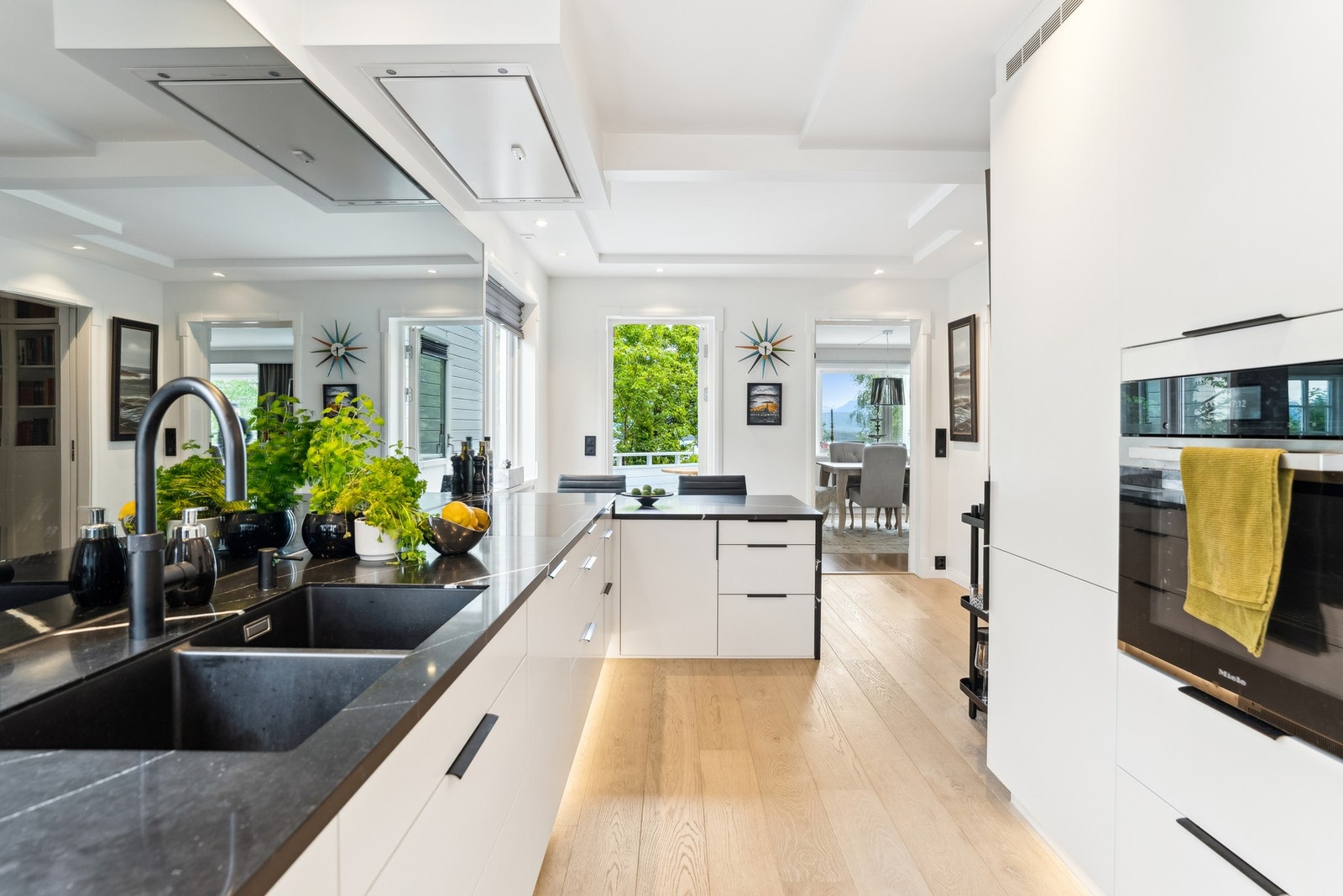 Speilet på kjøkkenet er spesialbestilt etter mål i sotet utførelse. Integrert stekeovn med damp, koketopp, oppvaskmaskin og lekkasjesikring - alt utført i en gjennomført og praktisk stil. Galleribilde