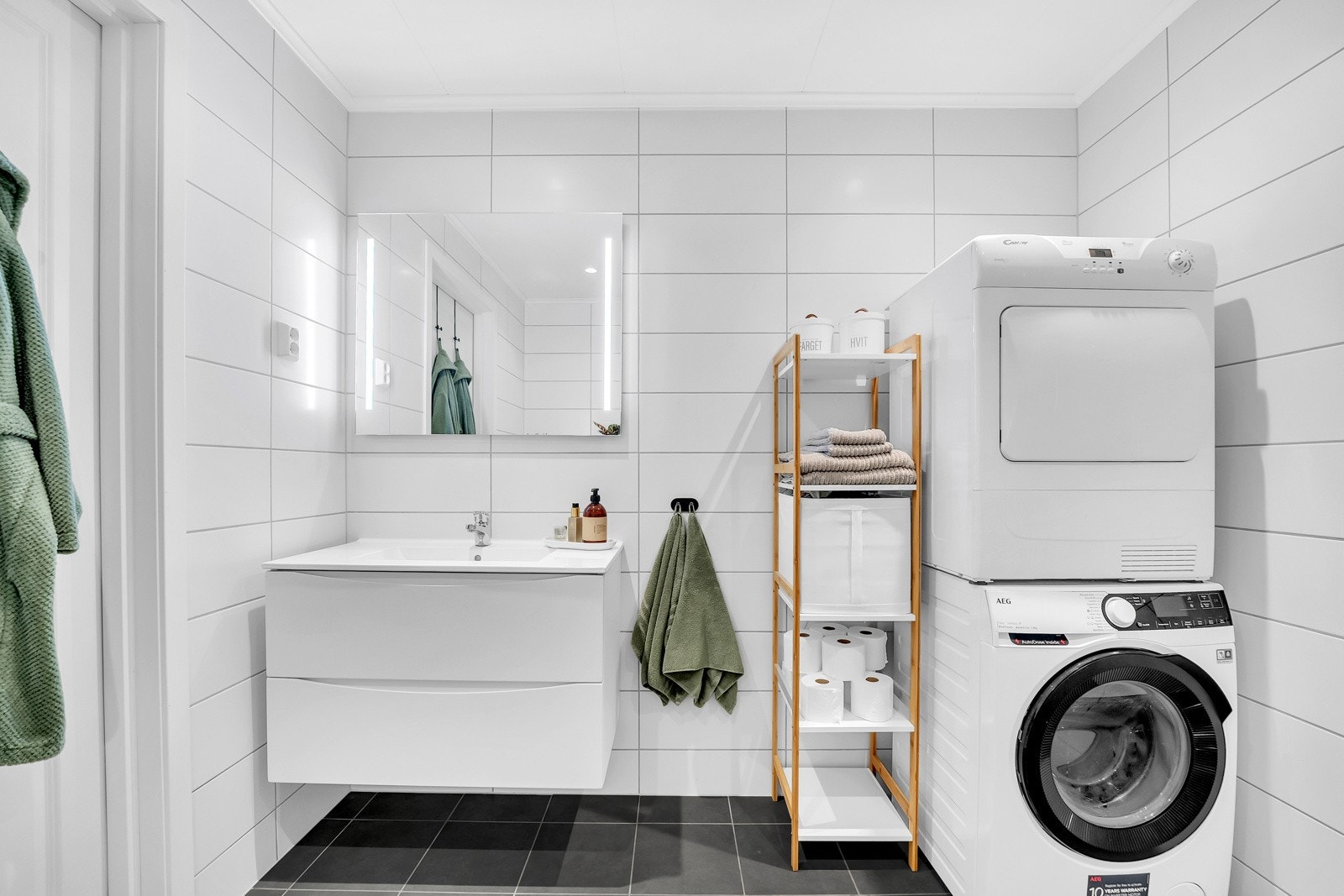 Badet er pent flislagt og har varmekabler. Her finner du alt av moderne baderomsmøbler, i tillegg til opplegg for vaskemaskin. Benkeskap med glatte fronter sørger for plass til oppbevaring av dine toalettartikler. Galleribilde