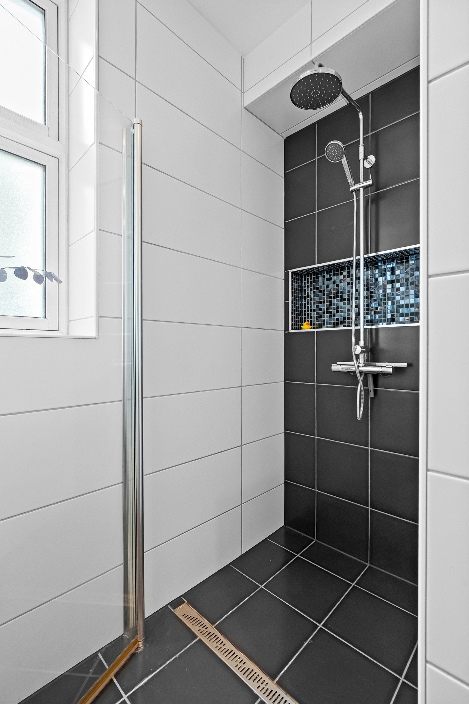 Dusjhjørne med innfellbare glassdører og dusjarmatur med hånddusj og regndusj. Galleribilde