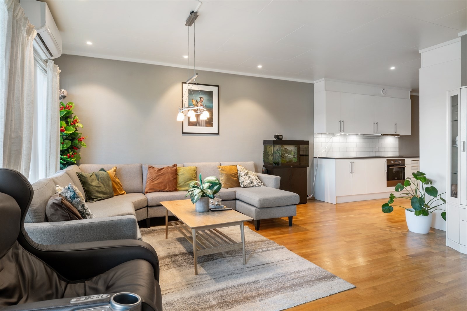 Åpen stue/kjøkken løsning med downlights i tak og lune, moderne farger på overflater. Galleribilde