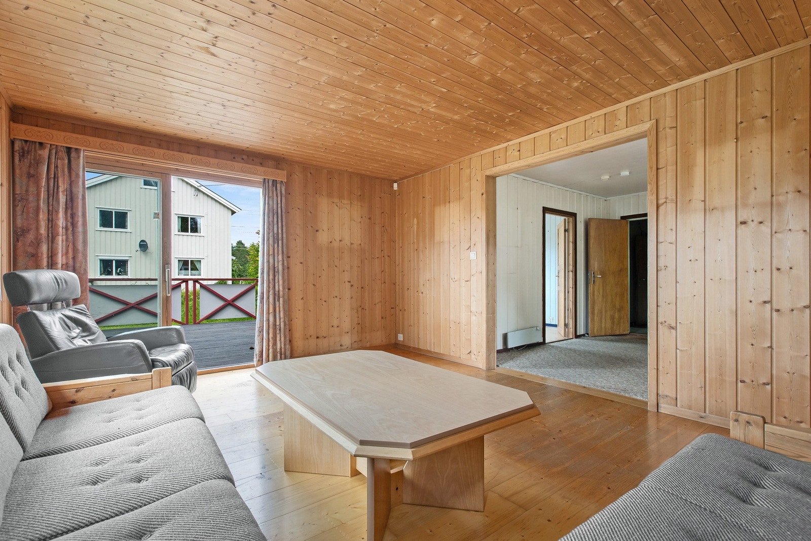 Vegger i den påbygde stuedelen består av ubehandlet panel. Innsyn til stuen som er i den opprinnelige delen av huset. Galleribilde