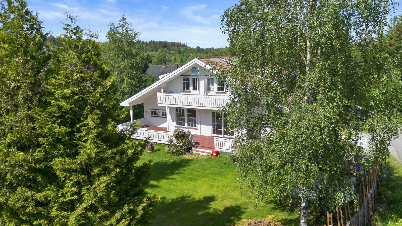 Tomten er pent opparbidet med grønne gressplener og diverse beplantning. Galleribilde