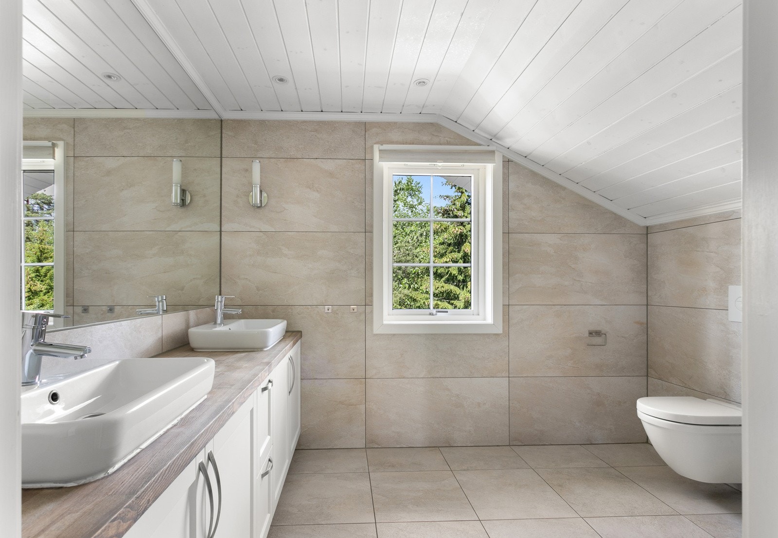 Baderommet har lys innredning, dobbel servant og veggmontert toalett. Galleribilde