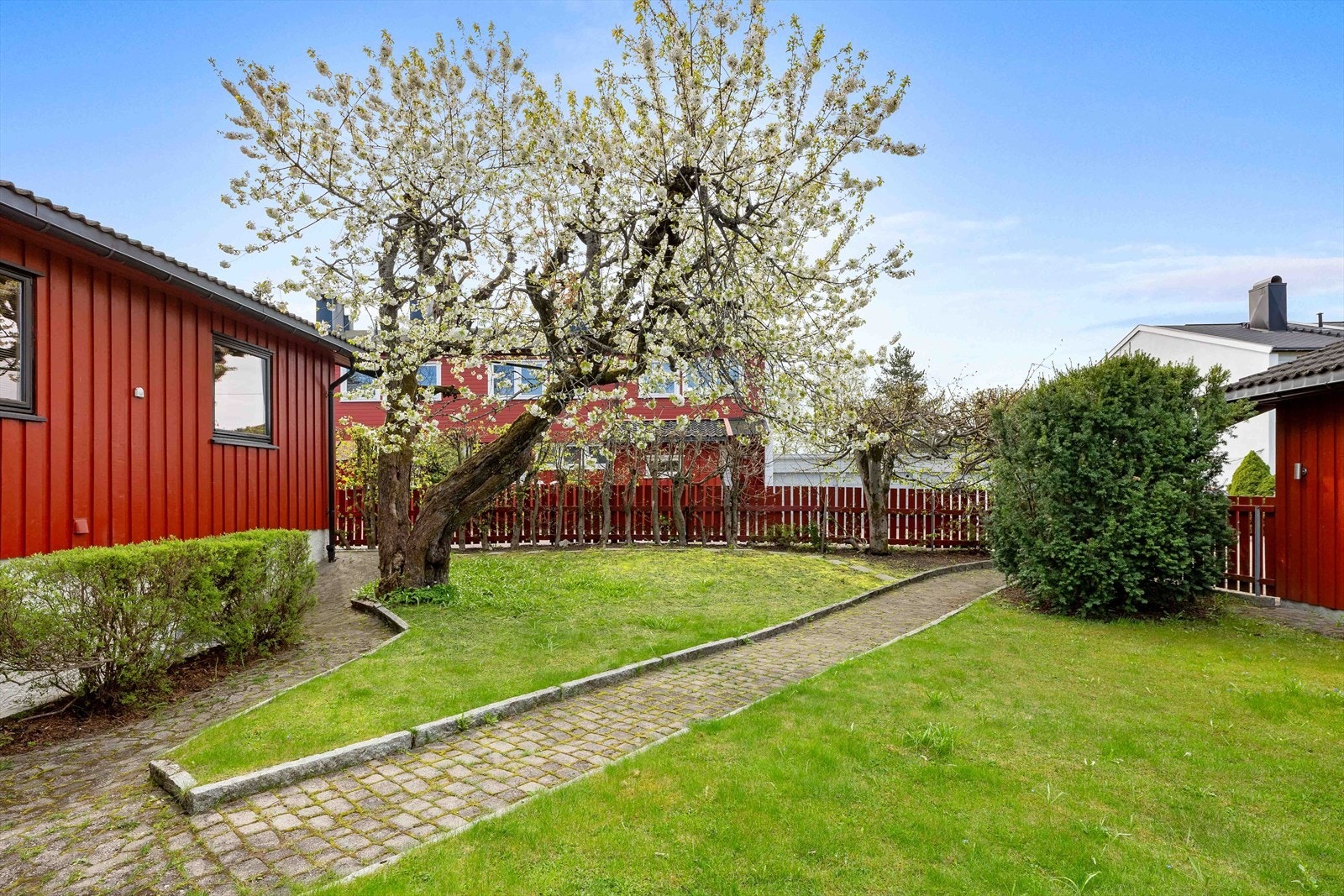 Eiendommen ligger tilbaketrukket med begrenset innsyn og byr på et frodig og solrikt uteområde - ideelt for både barnelek, sosiale sammenkomster og avslappende dager i hagen. Galleribilde