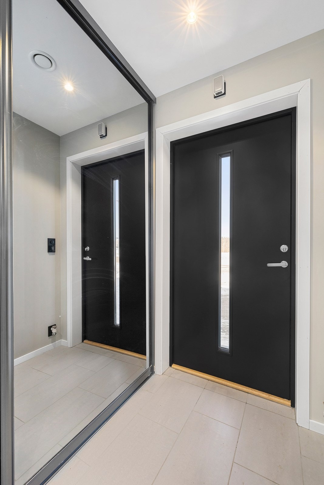 Romslig gang med skyvedørsgarderobe i speil. Gulvet er fliset og har varmekabler. Galleribilde