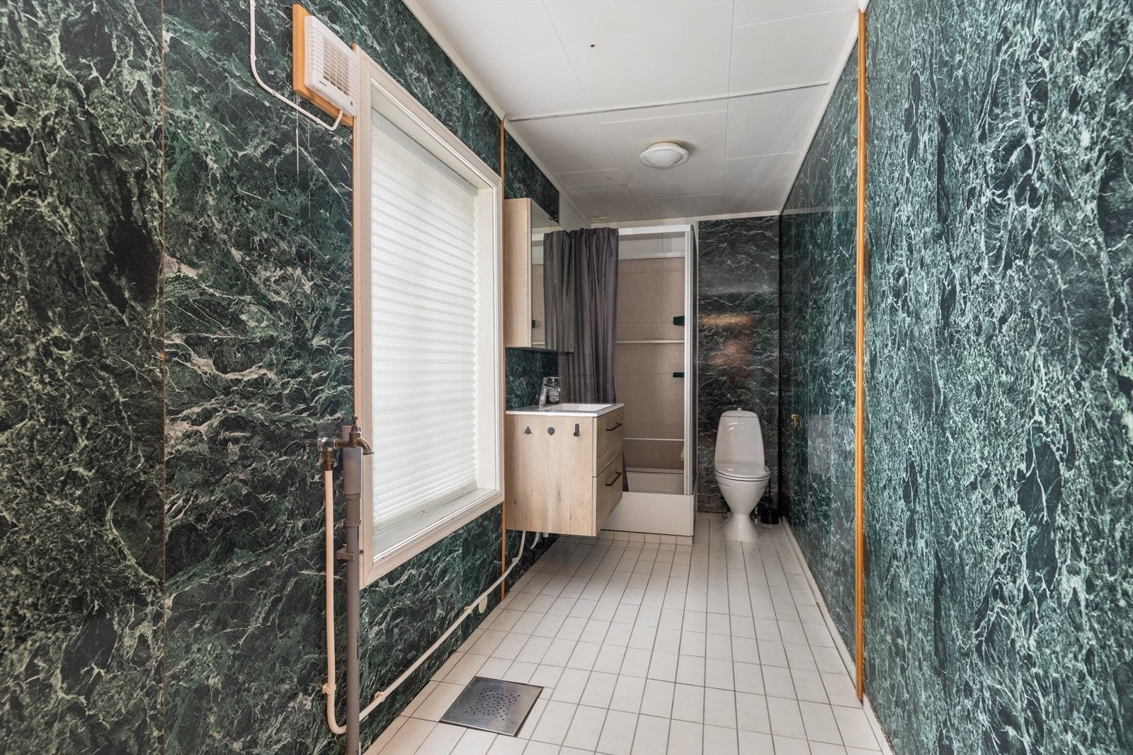 Det er varmekabler i gulv med flis på gulv og respatexplater på vegger. Her er det toalett, dusjkabinett og innredning med heldekkende vask, underskuffer og overskap med speildører. Det er opplegg for vaskemaskin og rommet er mekanisk ventilert. Galleribilde