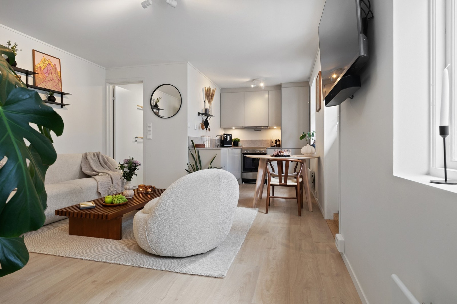 Dagslyset som strømmer inn via store, nordøstvendte vindusflater gjenspeiles fint i de hvitmalte overflatene, og allrommet har lys, enstavs laminat fra 2024 på gulvet. Galleribilde