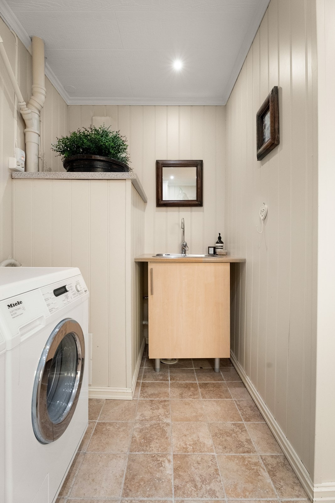 Vaskerommet har opplegg for vaskemaskin og tørketrommel, og benkinnredning med utslagsvask. Galleribilde