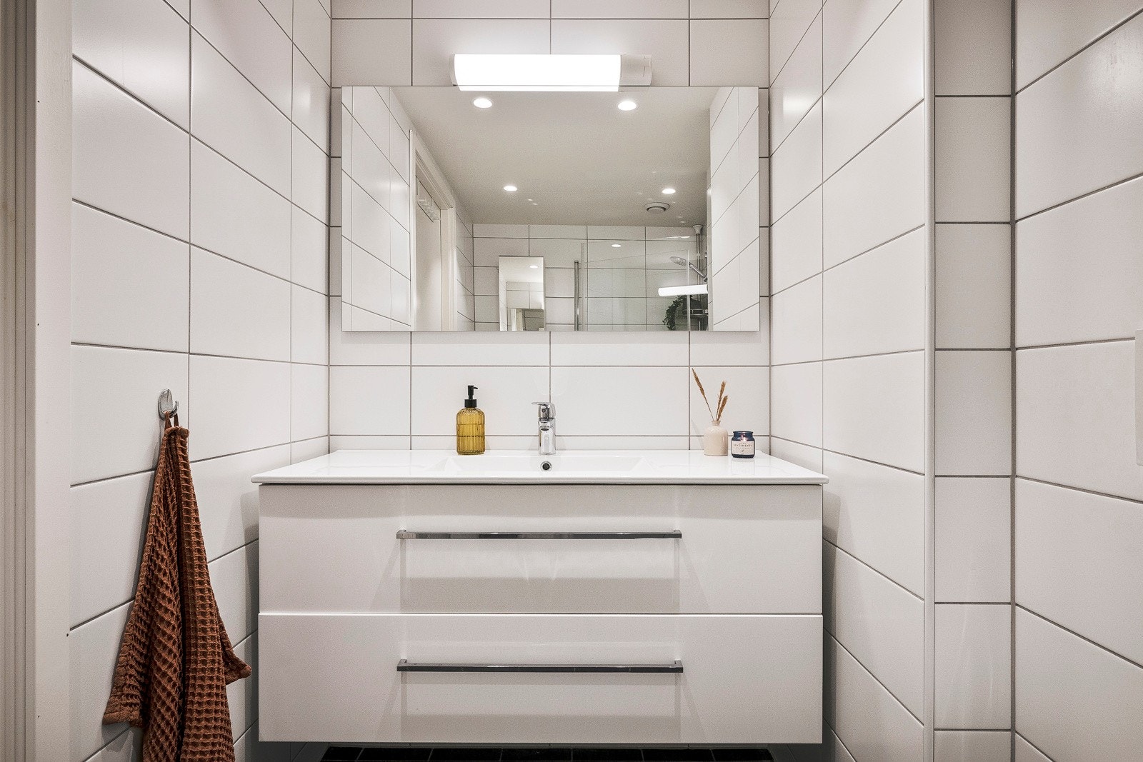 Badet har varmekabler i gulv og inneholder baderomsinnredning med nedfelt servant, vegghengt toalett og dusjhjørne. Galleribilde