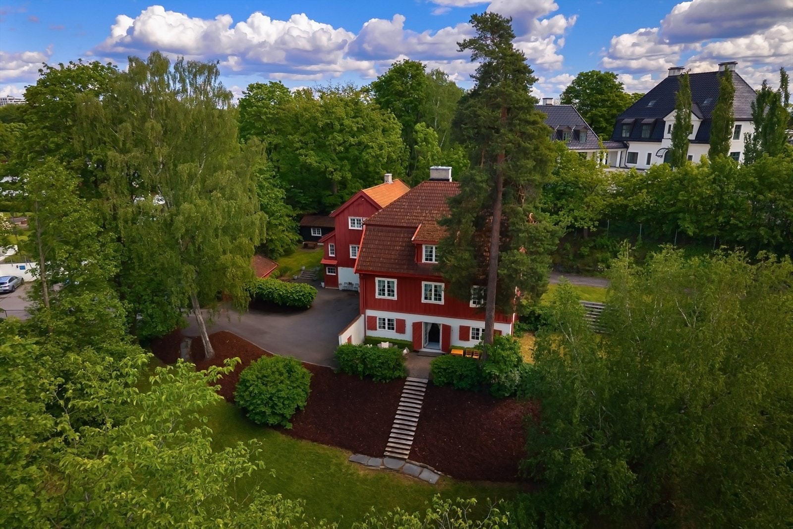 Tomten er skrånende, og opparbeidet med hage, trær, to gårdsplasser og noe naturtomt Galleribilde