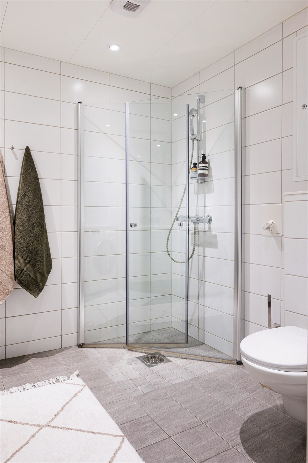 Badet er innredet med vegghengt toalett, servant med underskap og dusjhjørne med svingbare glassdører. Galleribilde