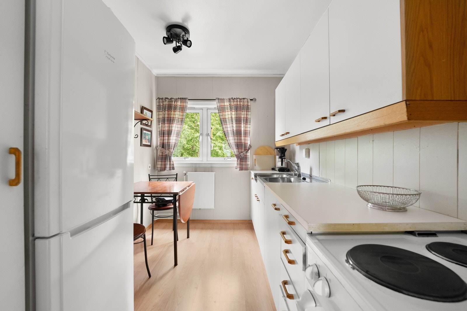 Innredningen har god oppbevaring, hvite, glatte fronter og dobbel oppvaskkum nedfelt i en laminert benkeplate Galleribilde