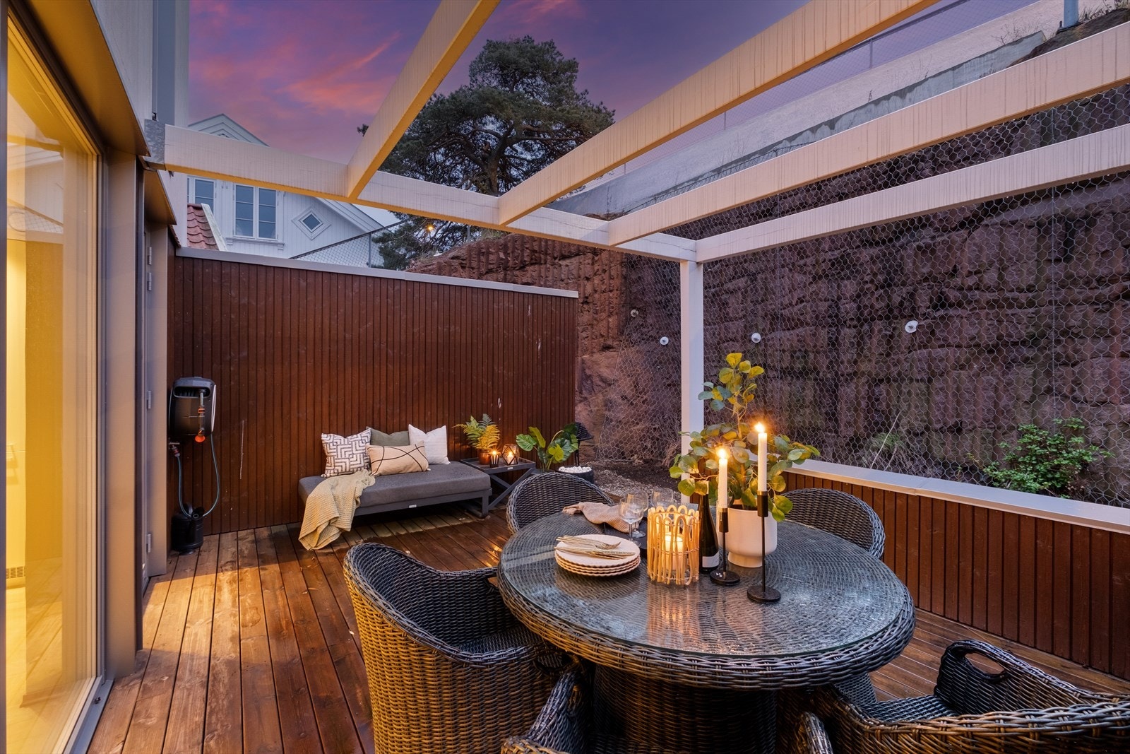 Terrassen er skjermet med høye levegger og har en pergoladekket del som gir både stemning og ly Galleribilde