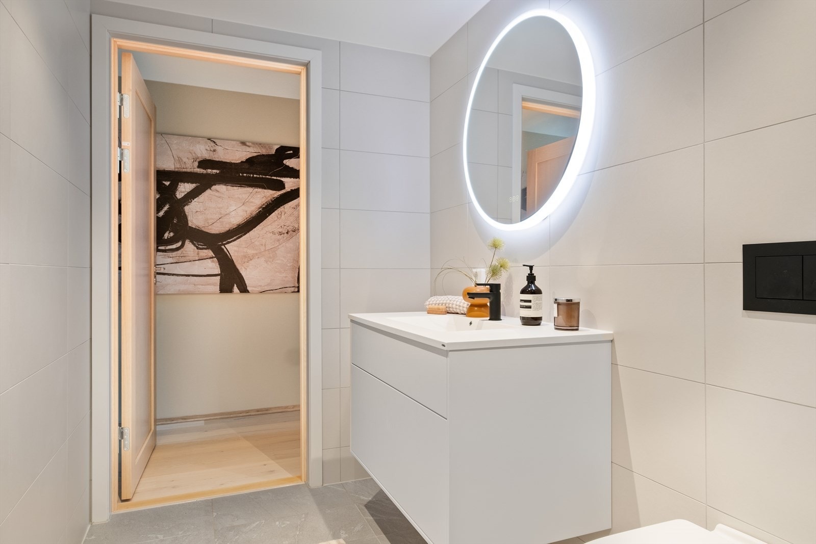 Begge badene har vegghengte toaletter og dusjhjørner med rette, innfellbare glassdører med sorte detaljer. Dusjarmaturene er sorte og består av både hånddusj og regnfallsdusj Galleribilde