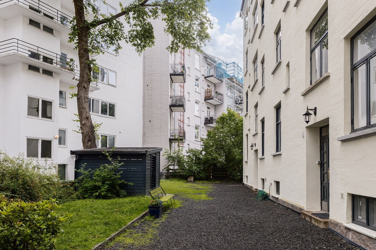 Pent opparbeidet bakgård med sittegrupper og grill, plen og beplantning. Galleribilde
