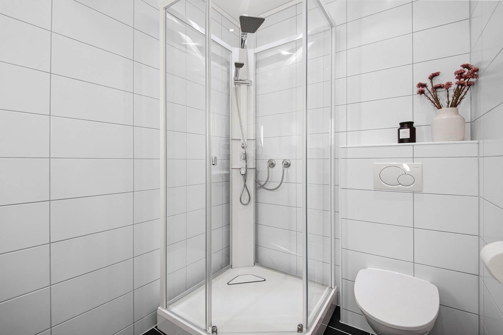 Badet er innredet med dusjkabinett, vegghengt toalett og baderomsinnredning med vask. Galleribilde