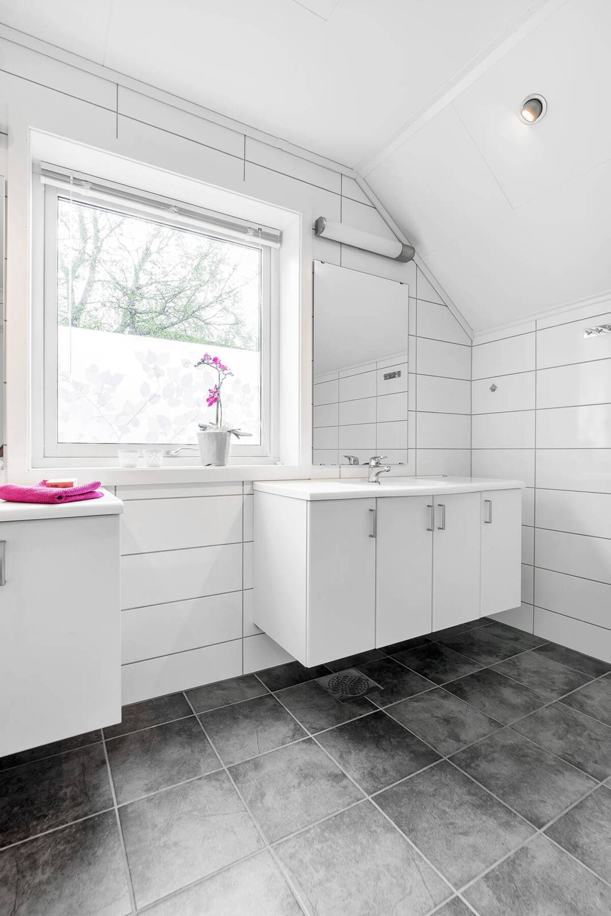 Badet er innredet med flis på gulv og vegger samt downlights i tak. Galleribilde