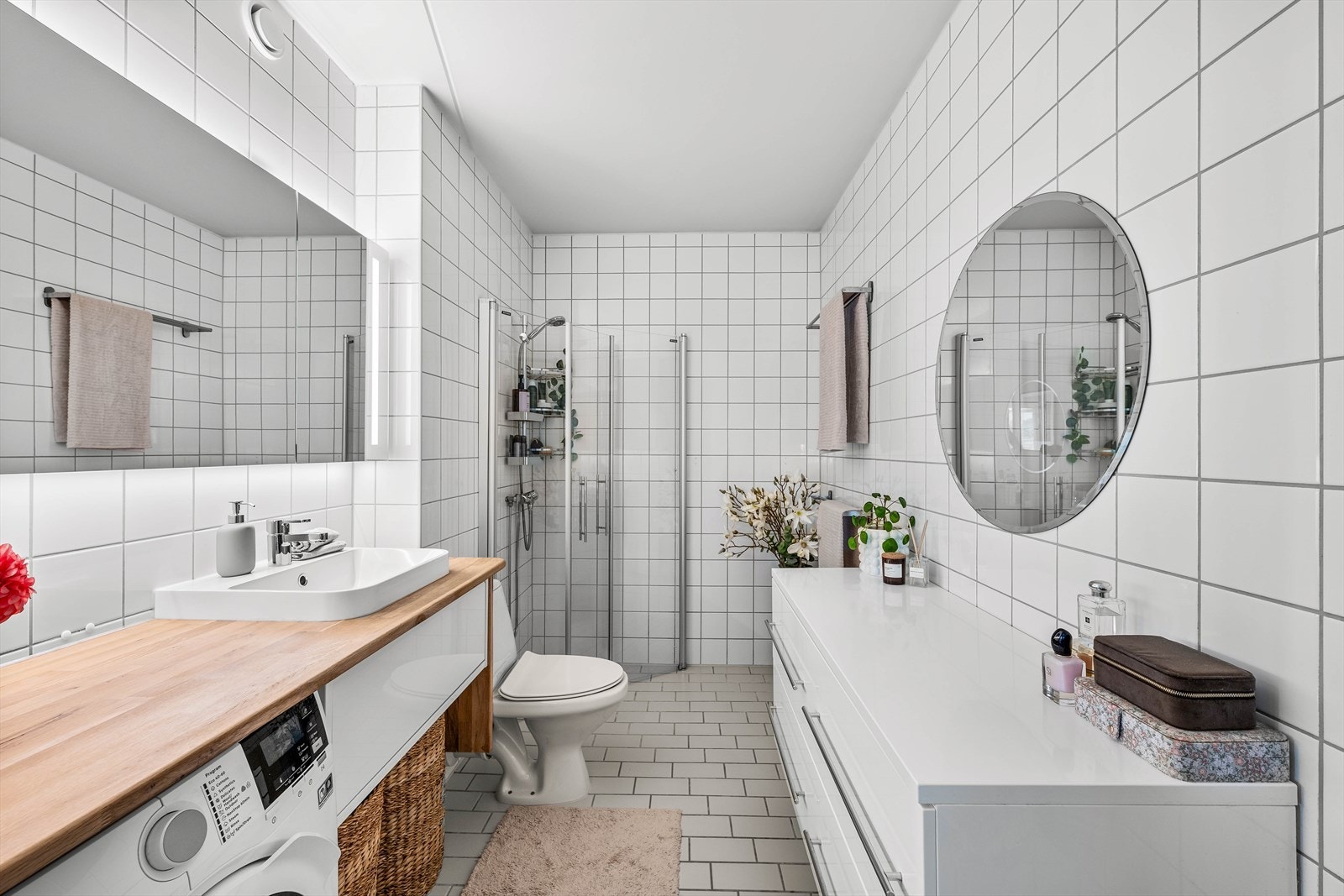 Flott helfliset baderom innredet med dusjhjørne, gulvmontert toalett og servant med speilskap. Opplegg for vaskemaskin. Galleribilde