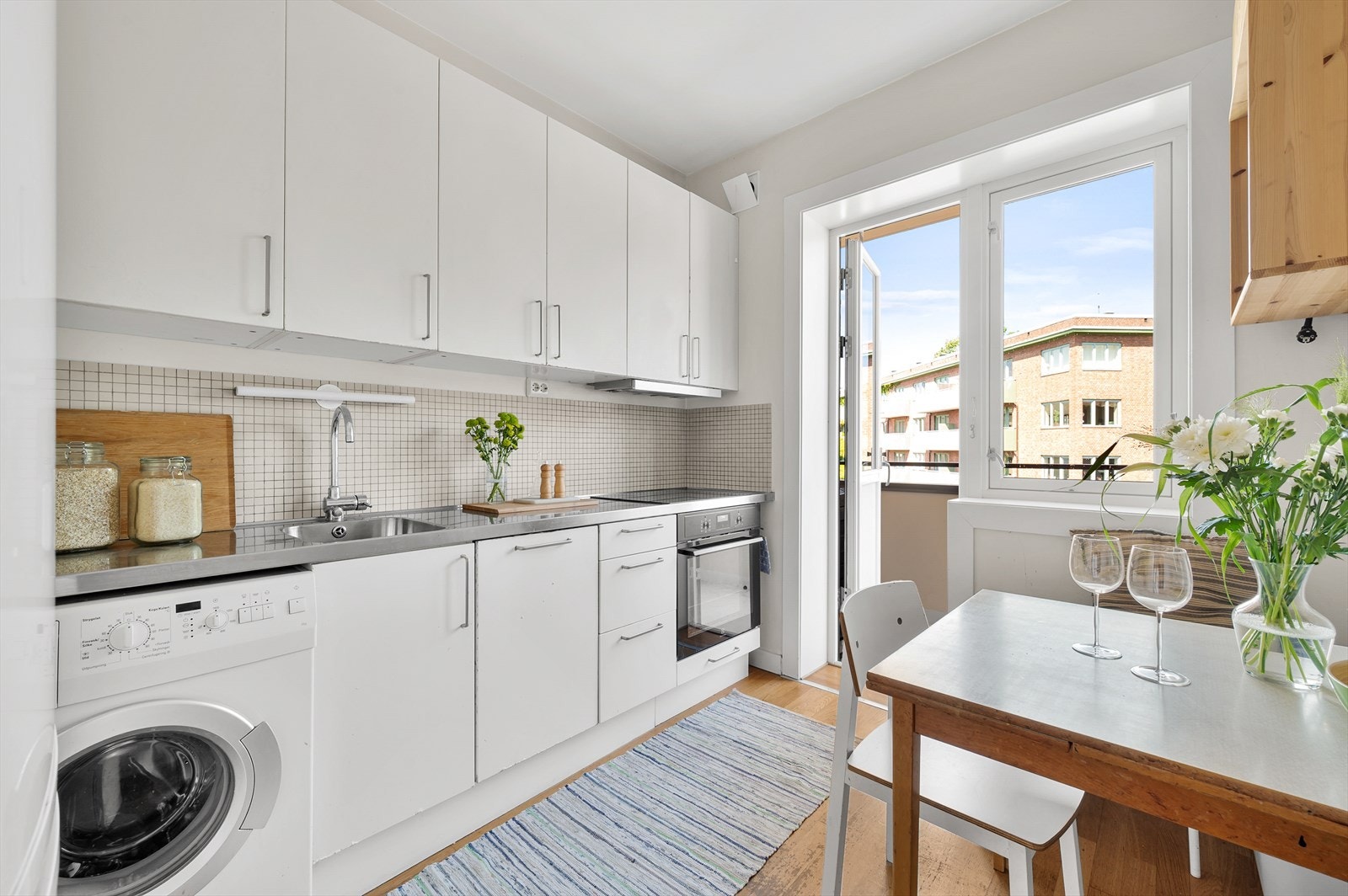 Koselig separat kjøkken. Innredning med glatte fronter og benkeplate av stål. Galleribilde