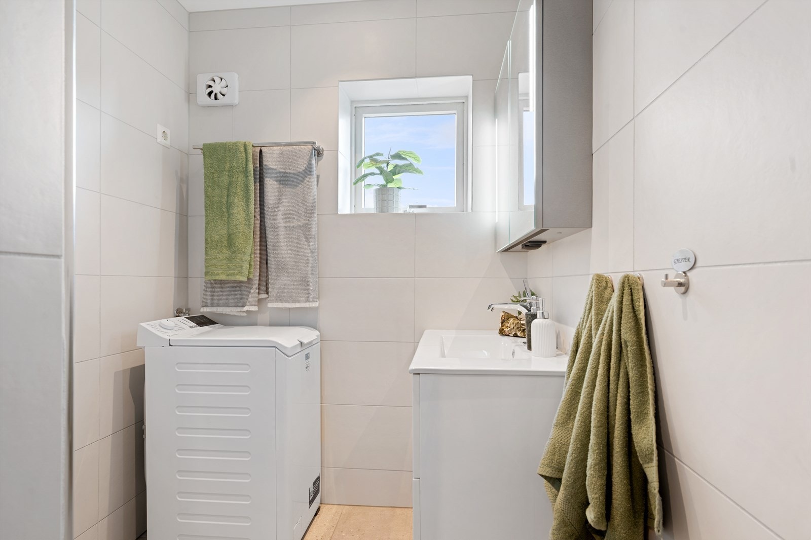 Badet har store moderne gulvfliser og tidløse avlange veggfliser. Moderne helservant på skuffeinnredning og speilskap med belysning. Galleribilde