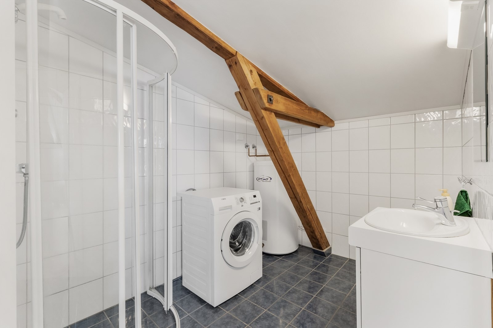 Baderom 2 med varmtvannstank i hjørnet, opplegg til vaskemaskin og dusjsone Galleribilde