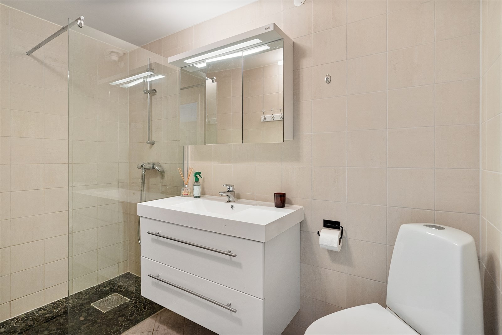 Bad i 2. etasje har varmekabler, toalett, helstøpt servant, skuffer under servant med slette fronter, dusjvegg i klart glass. Galleribilde