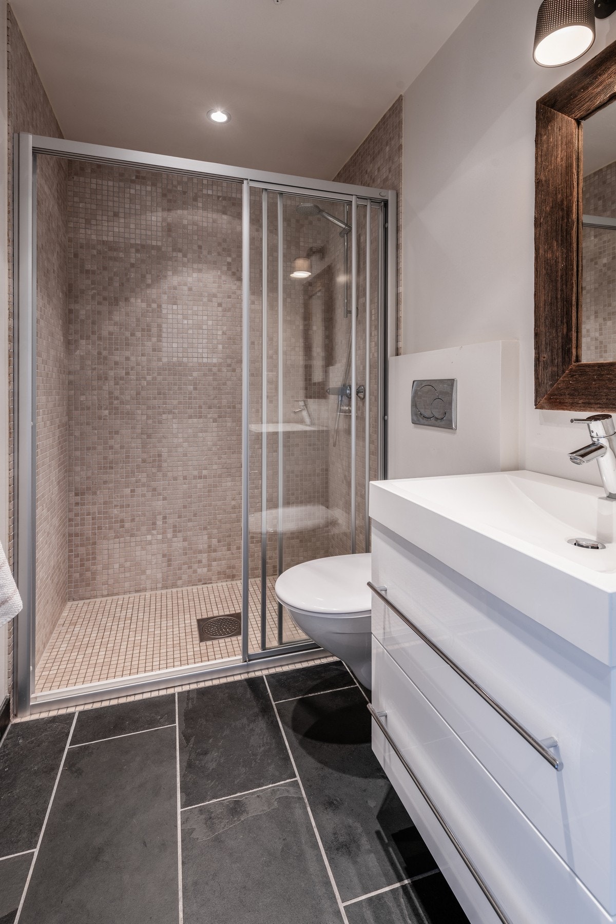 Lekkert bad med flislagt gulv og dusj Galleribilde